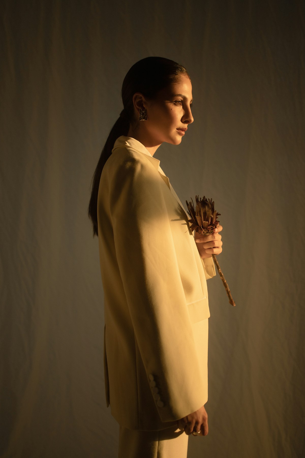 Cream tailoring and a dried flower in side light